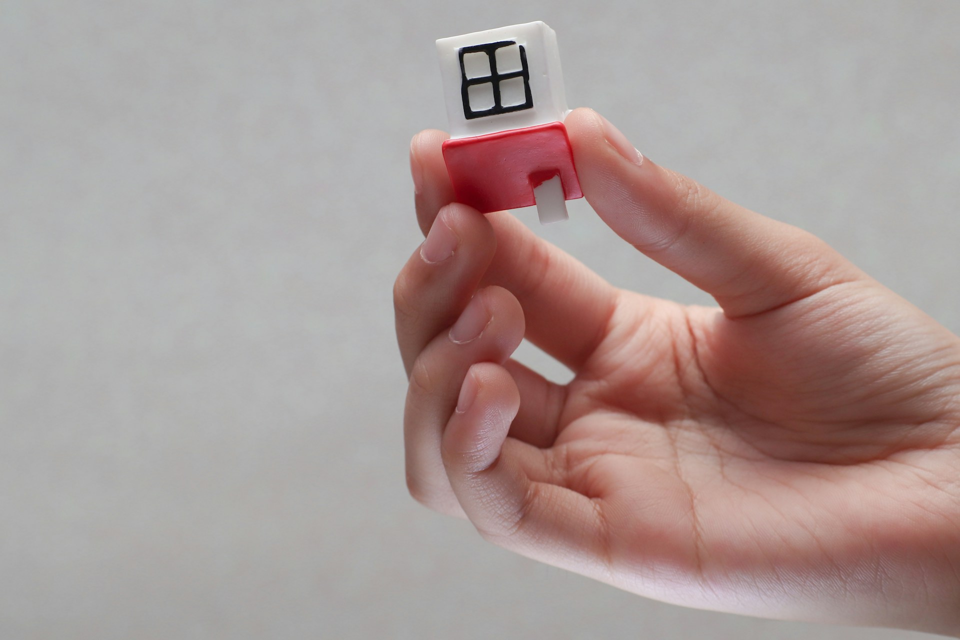 A hand holding a toy house