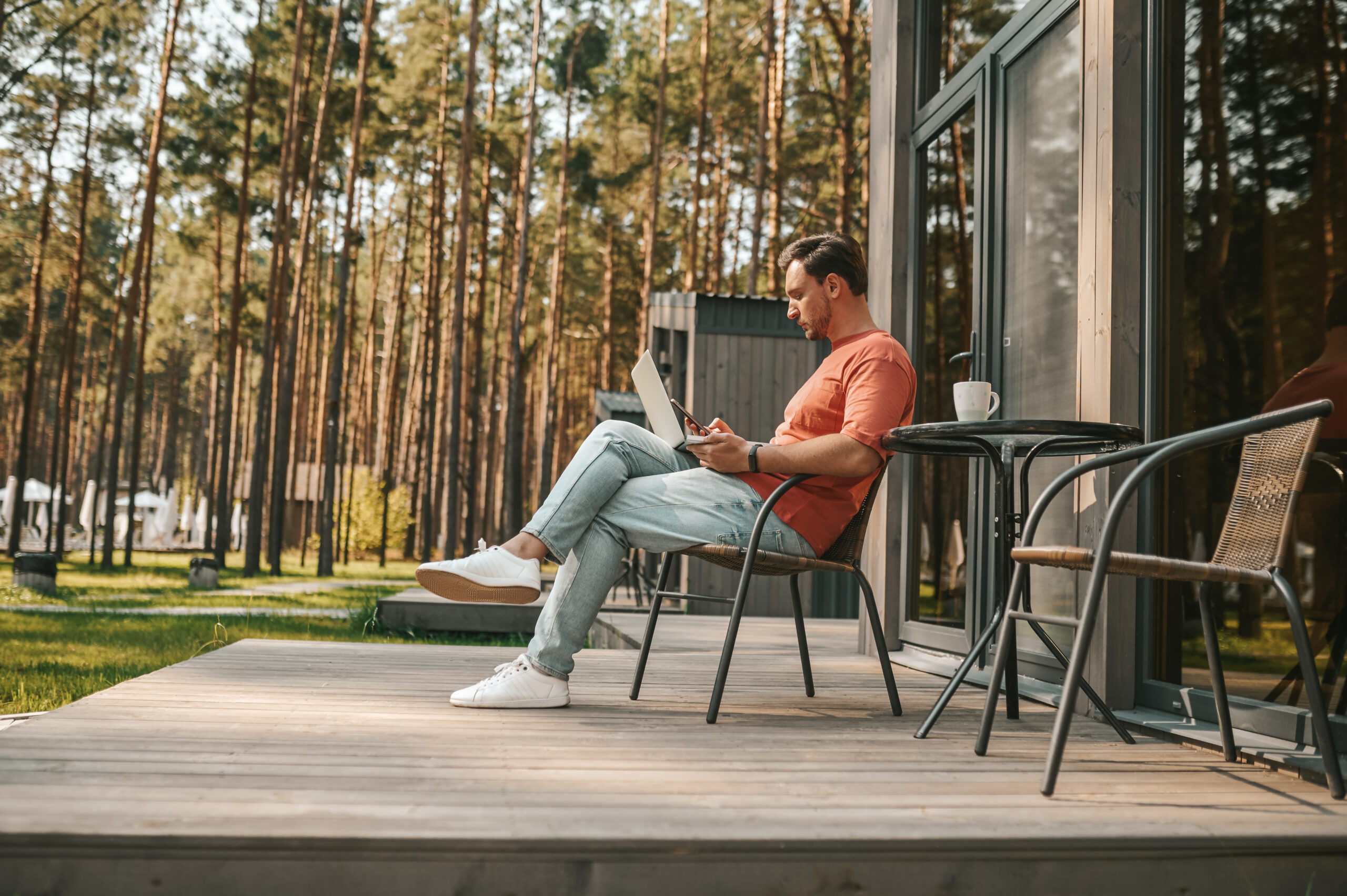 A young man with a laptop sitting outside and working online